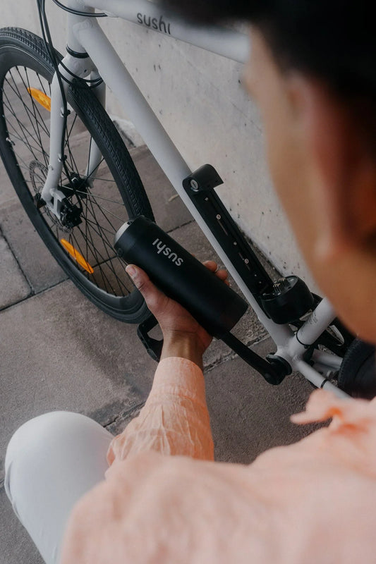 Person setzt Akku in ein SUSHI BIKES E-Bike ein