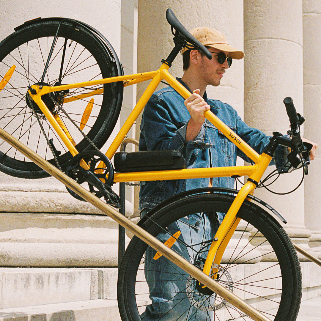 Maki 3.0+ Lava, Mann trägt das gelbe E-Bike eine Treppe herunter