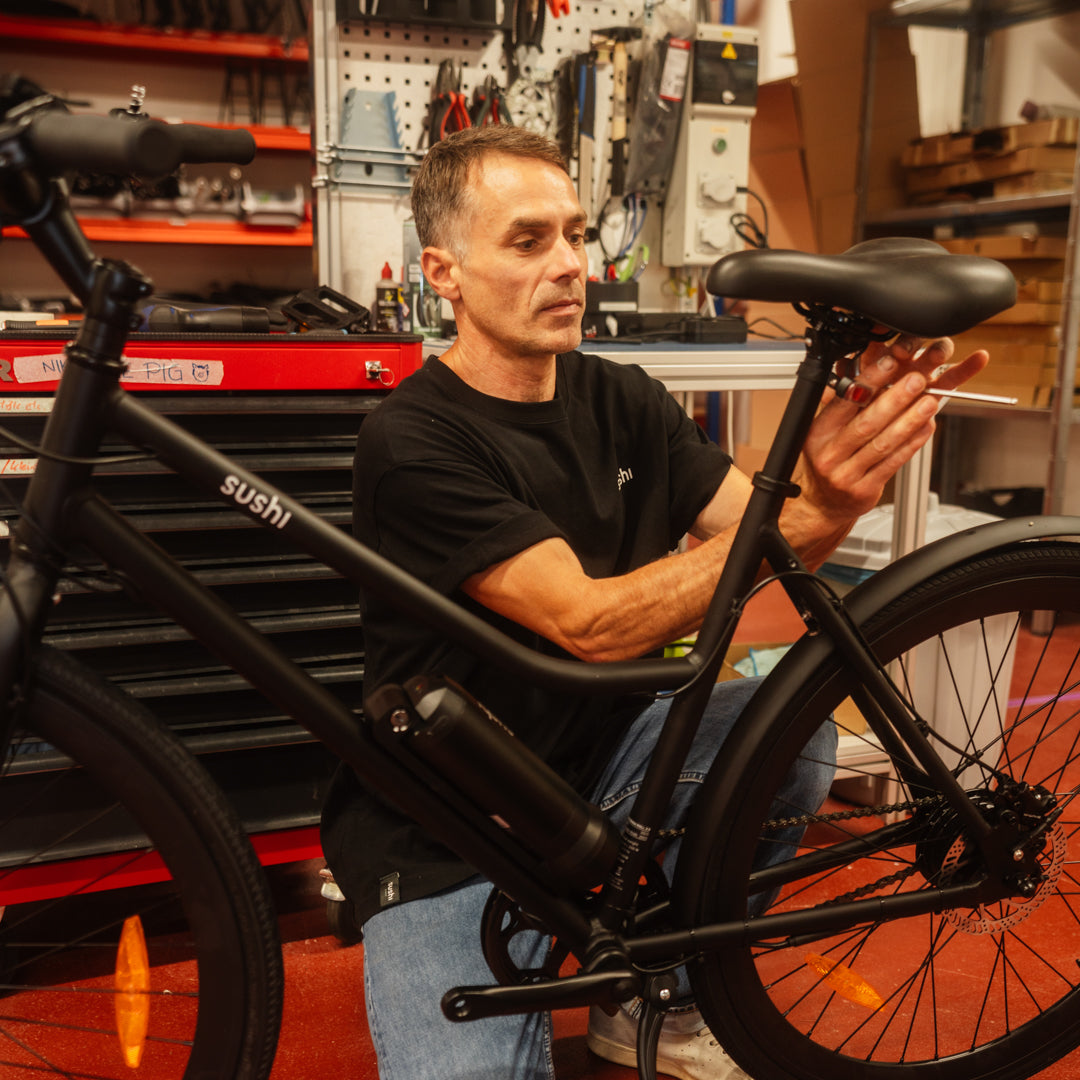 Mitarbeiter im Refurbishment Center von SUSHI BIKES wartet ein E-Bike für eine nachhaltige urbane Mobilitätslösung.