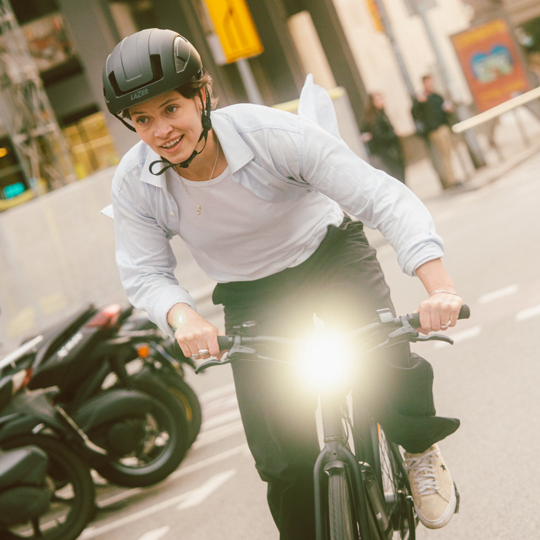 Frau fährt auf einer Straße mit ihrem SUSHI BIKE Maki 3.0+ und das eingeschaltete integrierte Vorderlicht scheint in die Kamera