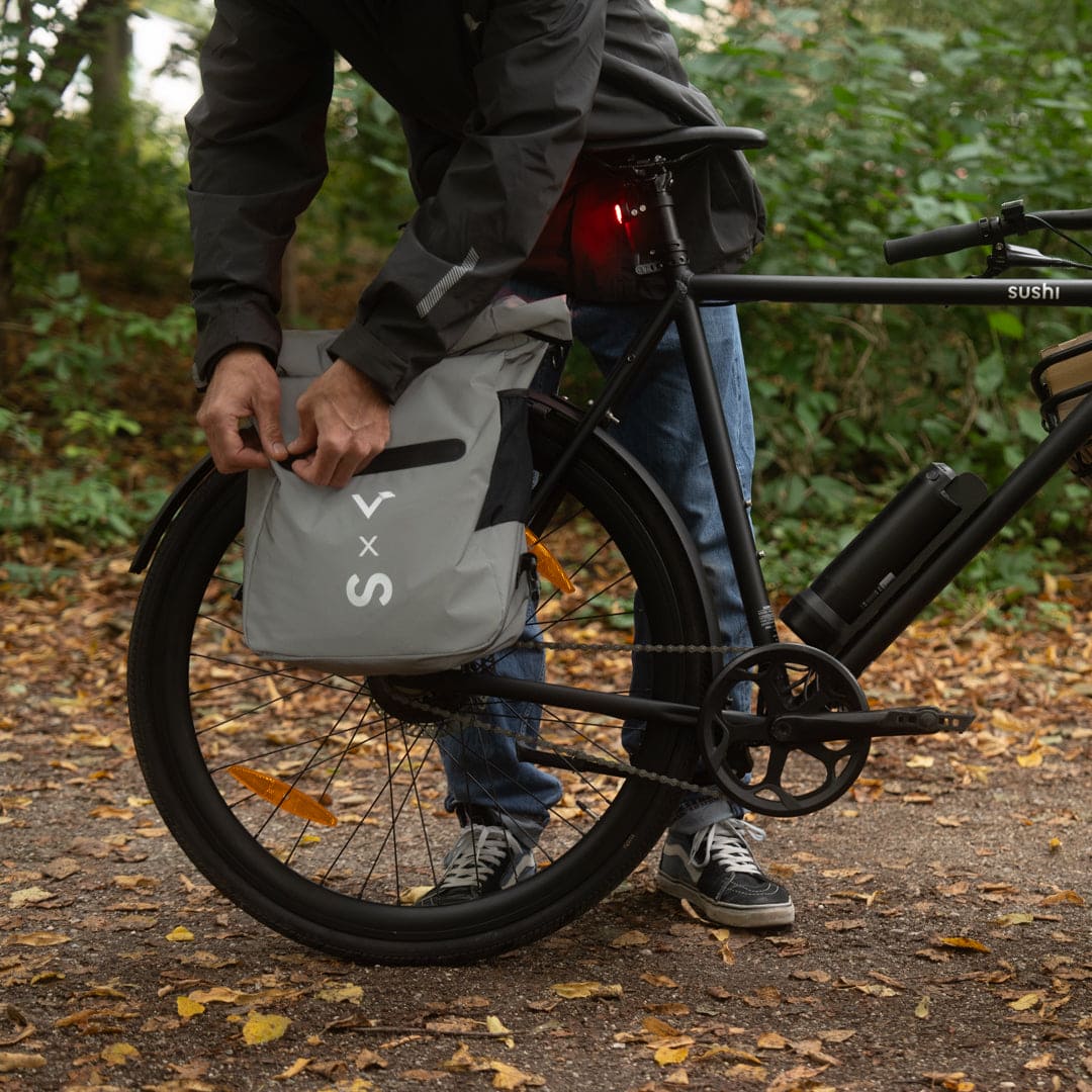 Person befestigt eine Fahrradtasche an der integrierten Halterung am hinteren Schutzblechs auf einem Waldweg