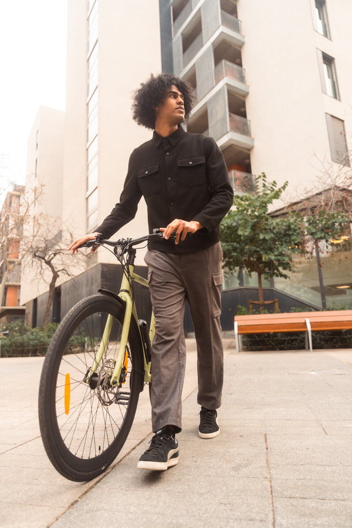 Mann schiebt E-Bike Maki 3.0+ in der Farbe Matcha durch die Stadt, modernes urbanes Umfeld