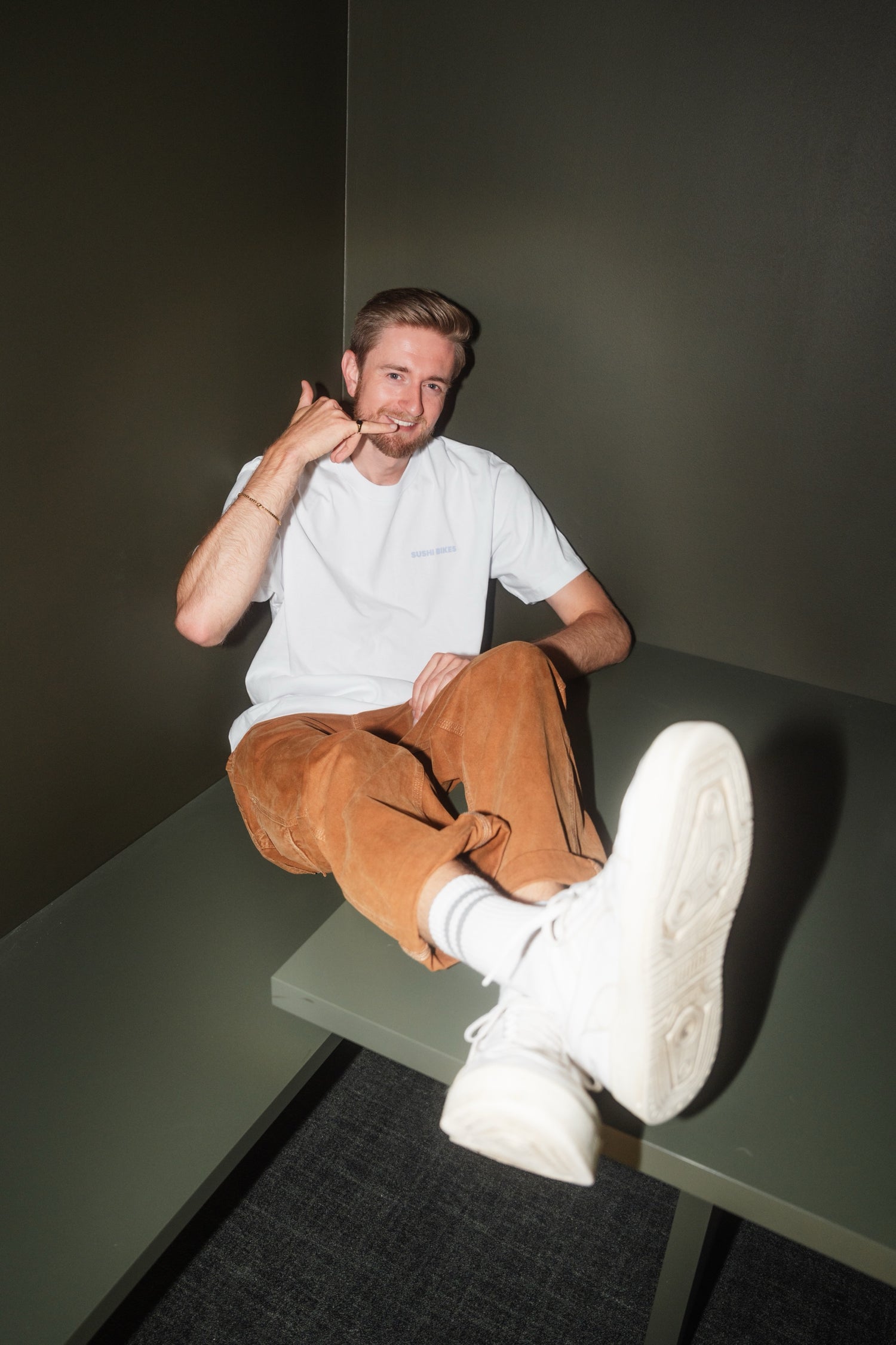 Markus von SUSHI BIKES macht “Ruf mich an”-Pose in lockerem Outfit – urbaner Style trifft E-Bike-Spirit