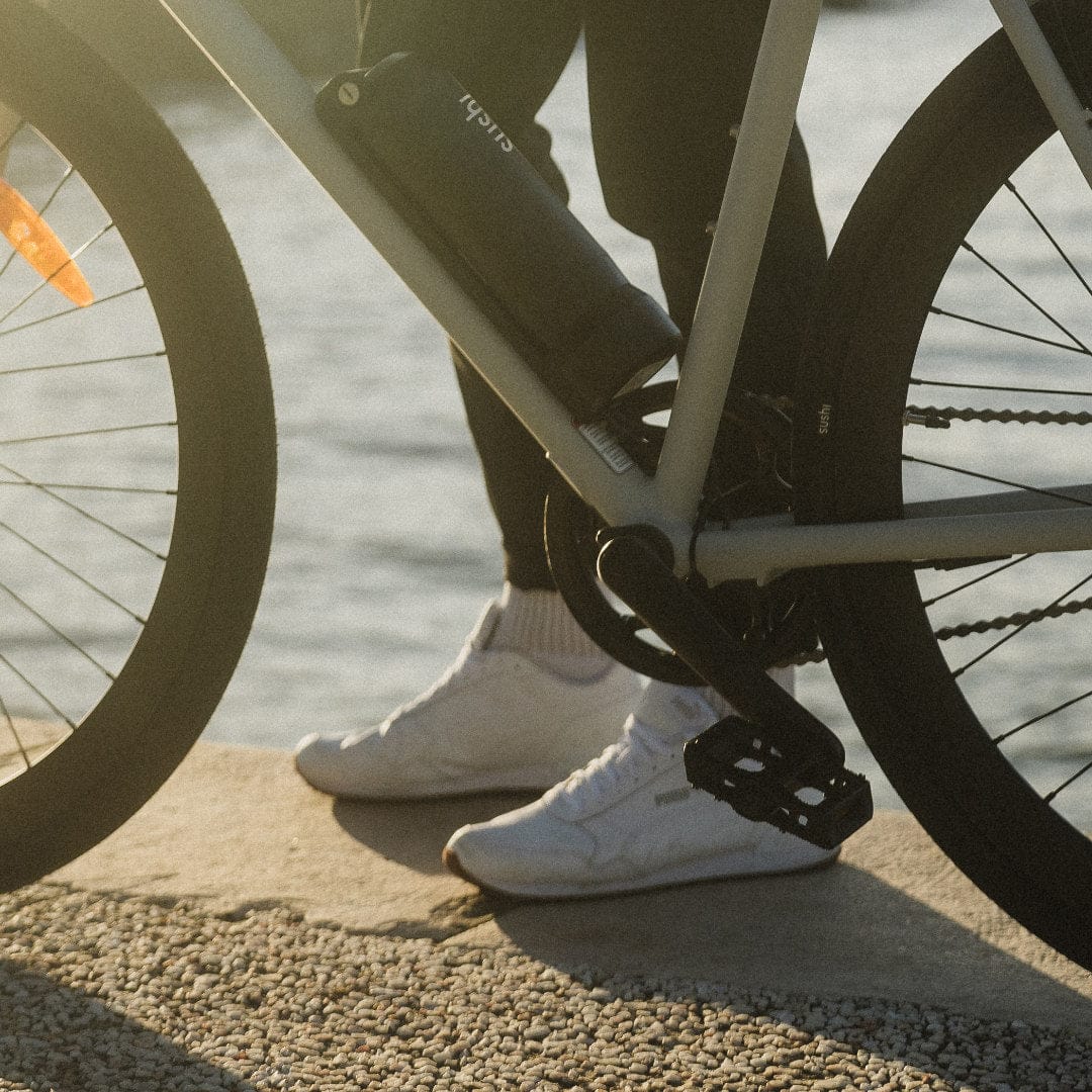 Fahrradfahrer mit weißen Sneakern steht hinter SUSHI BIKE mit montierten Pedalen