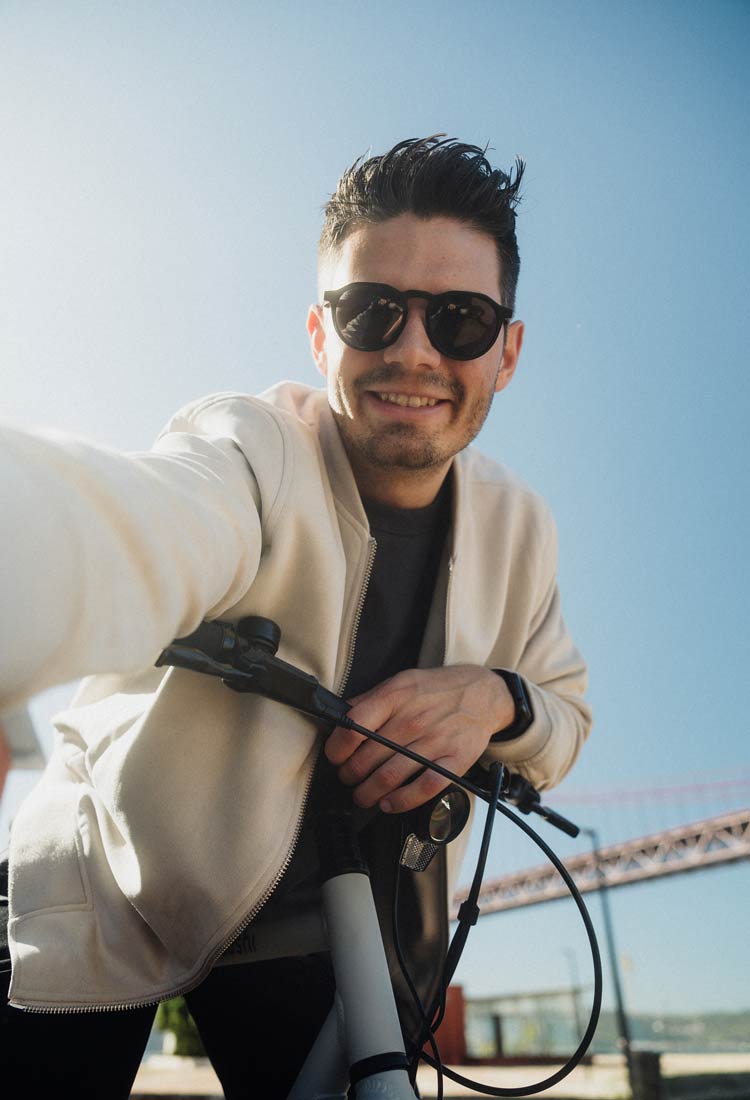 Gründer Andy sitzt auf einem grauen SUSHI BIKE, macht ein Selfie und lächelt in die Kamera