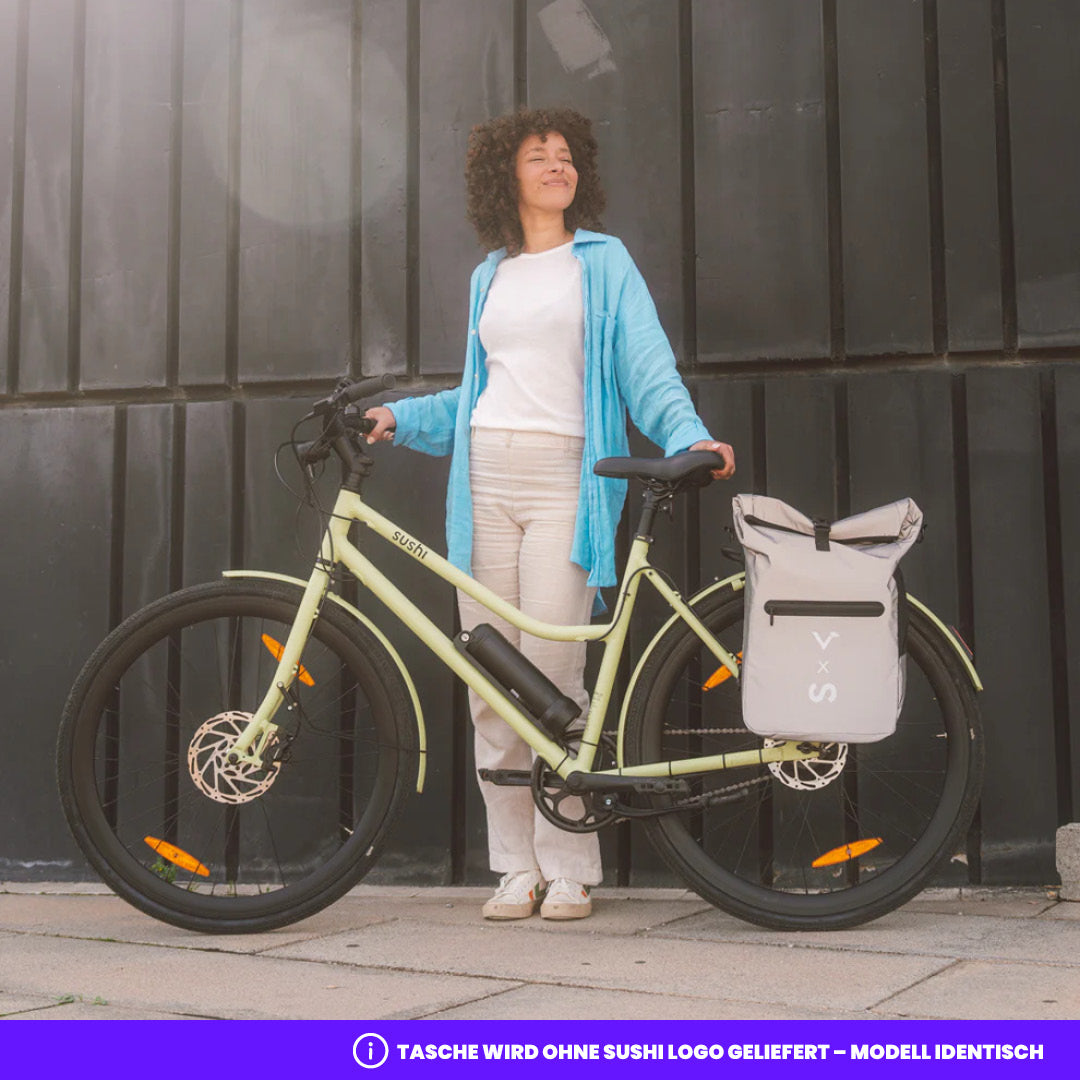 Frau steht neben einem matchafarbenen E-Bike von SUSHI BIKE mit grauer Valkental 3in1 Fahrradtasche