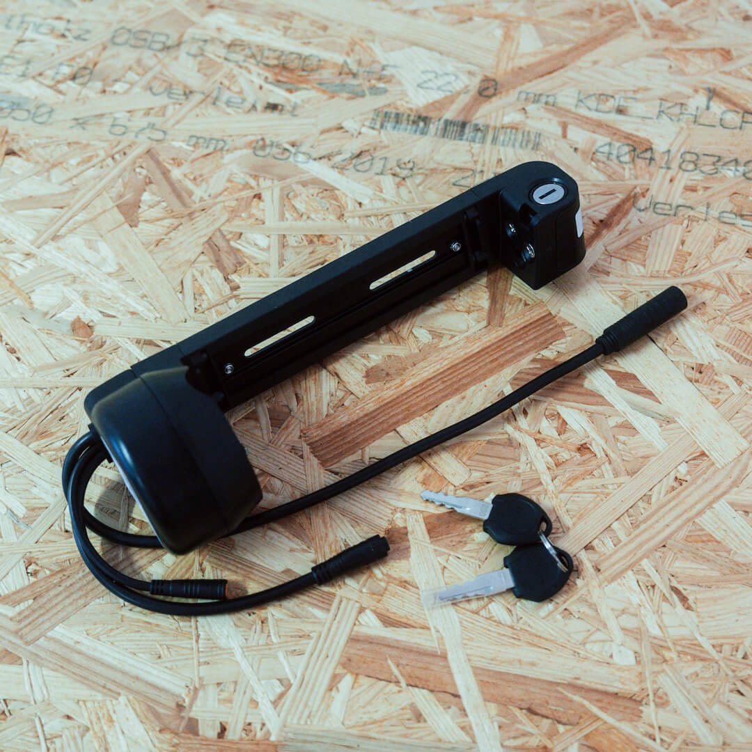 Akkuhalterung und zugehörige Schlüssel liegen auf einer Holzplatte