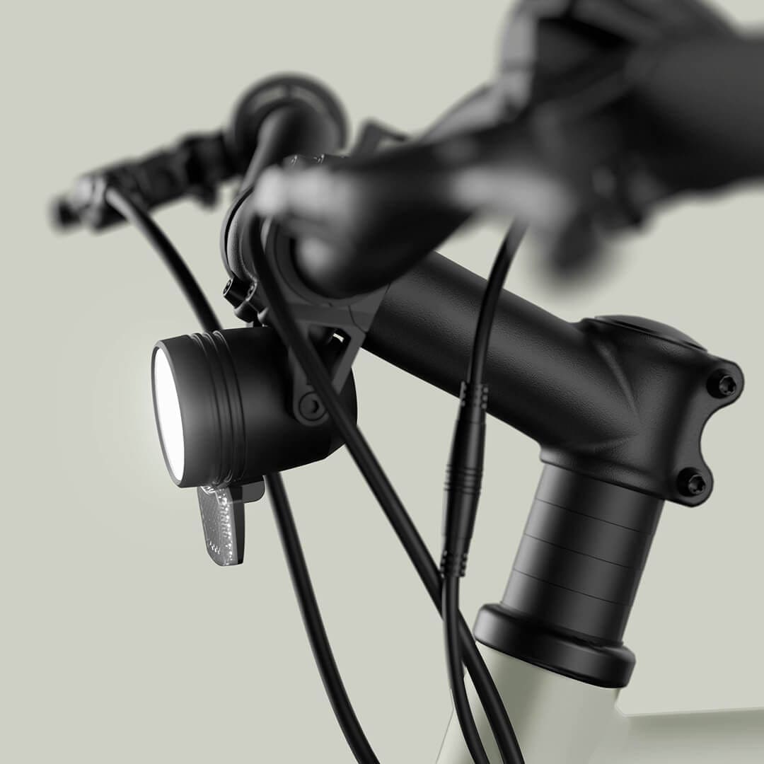 Seitenansicht des eingeschalteten Frontlichts und Lenker vom grauen E-Bike Maki 3.0