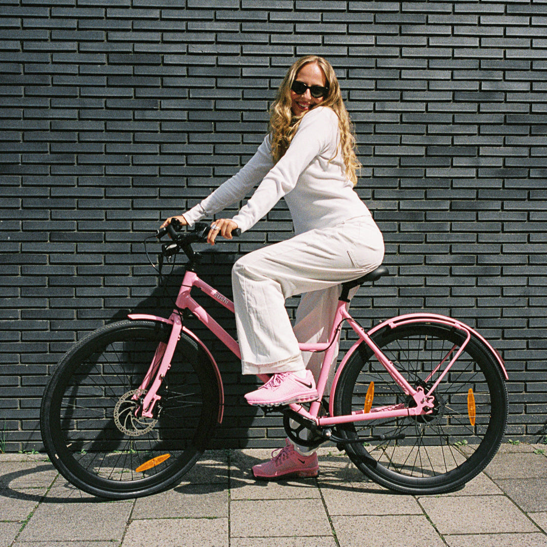 California Roll 3.0+ Bubblegum, auf dem eine Frau vor einer grauen Wand sitzt und in die Kamera lächelt