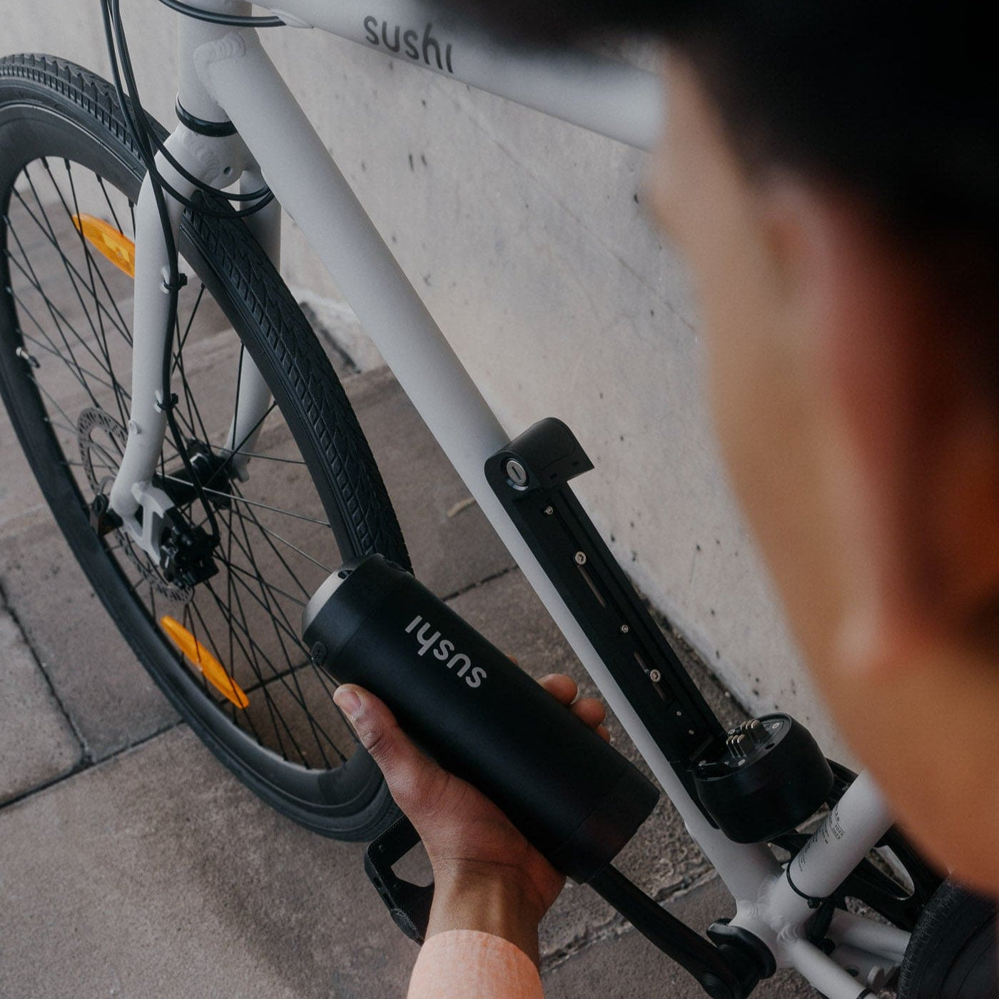 Mann hält herausnehmbarer Akku neben Akkuhalterung eines grauen E-Bike Maki 3.0