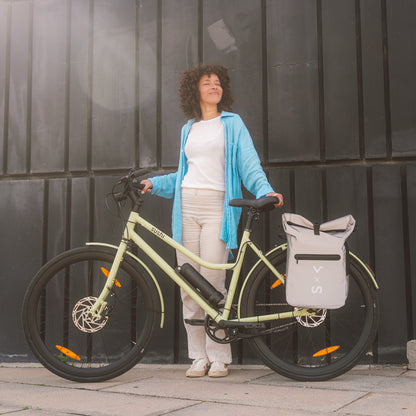 Frau steht neben einem matchafarbenen E-Bike von SUSHI BIKE mit grauer Gepäcktasche