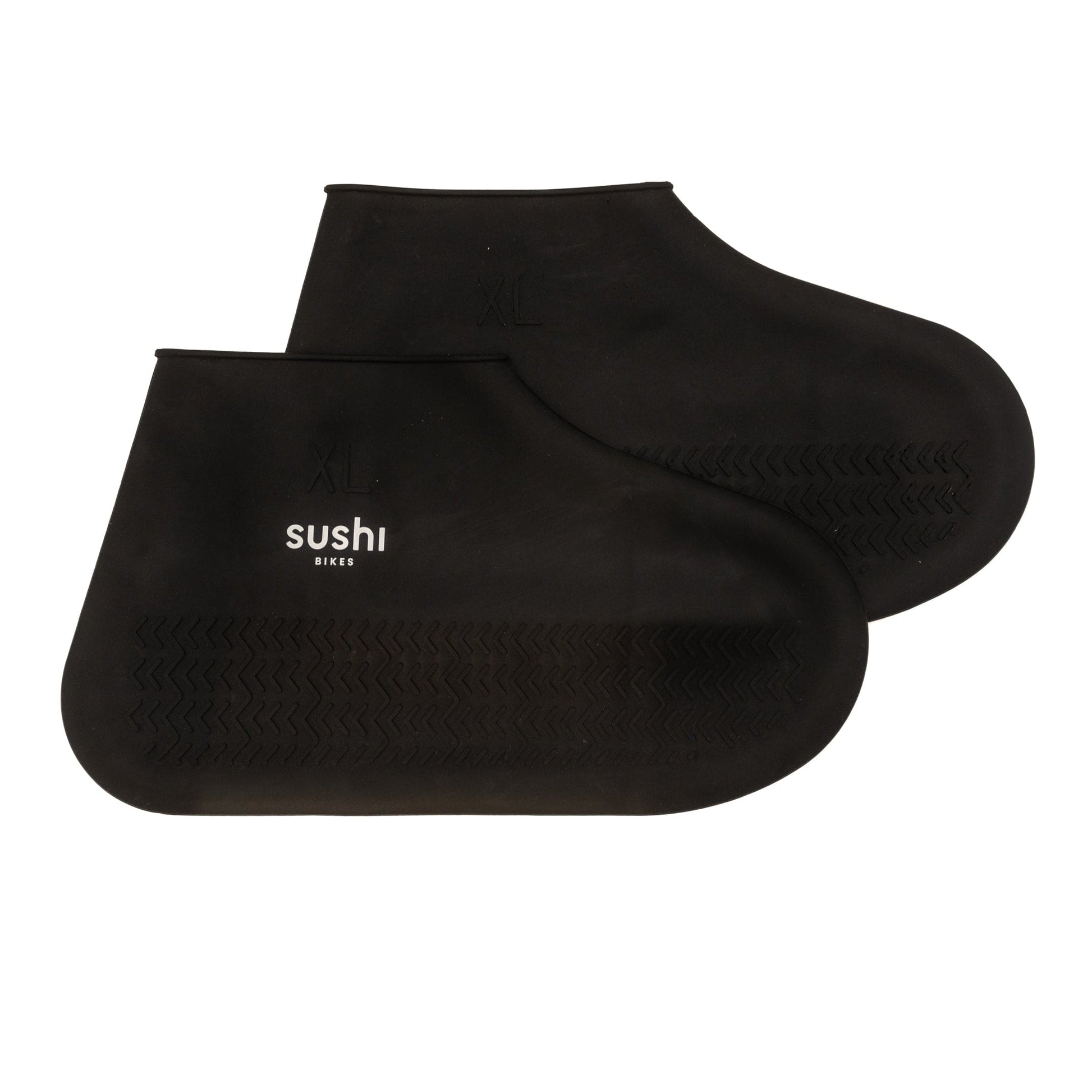 Detailaufnahme von SUSHI Schuhüberzieher getragen von einer Person beim Fahrradfahren auf nassem Asphalt