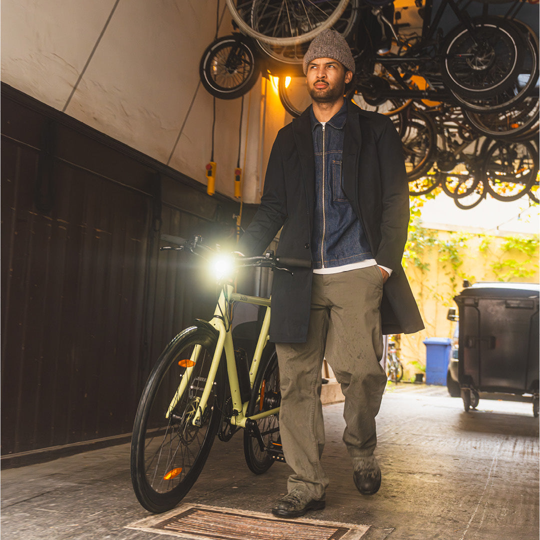 Maki 3.0+ Matcha, Mann steht neben E-Bike und Fahrradtasche in einem Hauseingang