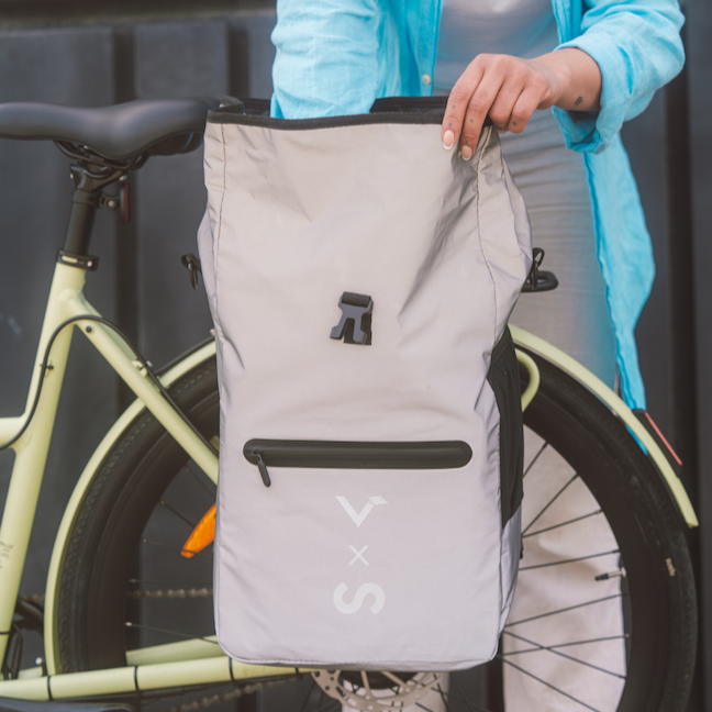 Frau greift in graue Fahrradtasche am Gepäckträger eines matchafarbenen E-Bikes