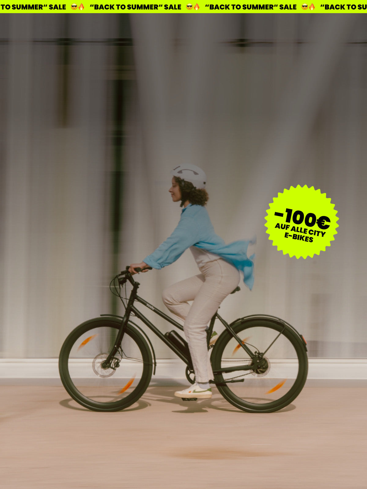 Frau mit weißem Helm fährt ein schwarzes E-Bike California Roll 3.0+ von SUSHI BIKES