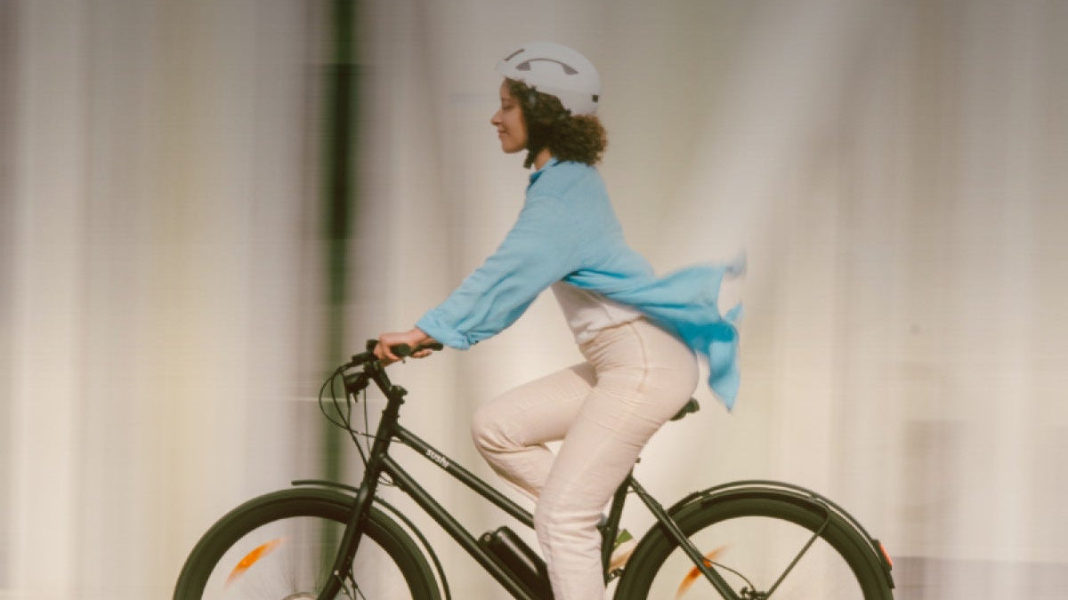Frau mit weißem Helm fährt ein schwarzes E-Bike California Roll 3.0+ von SUSHI BIKES