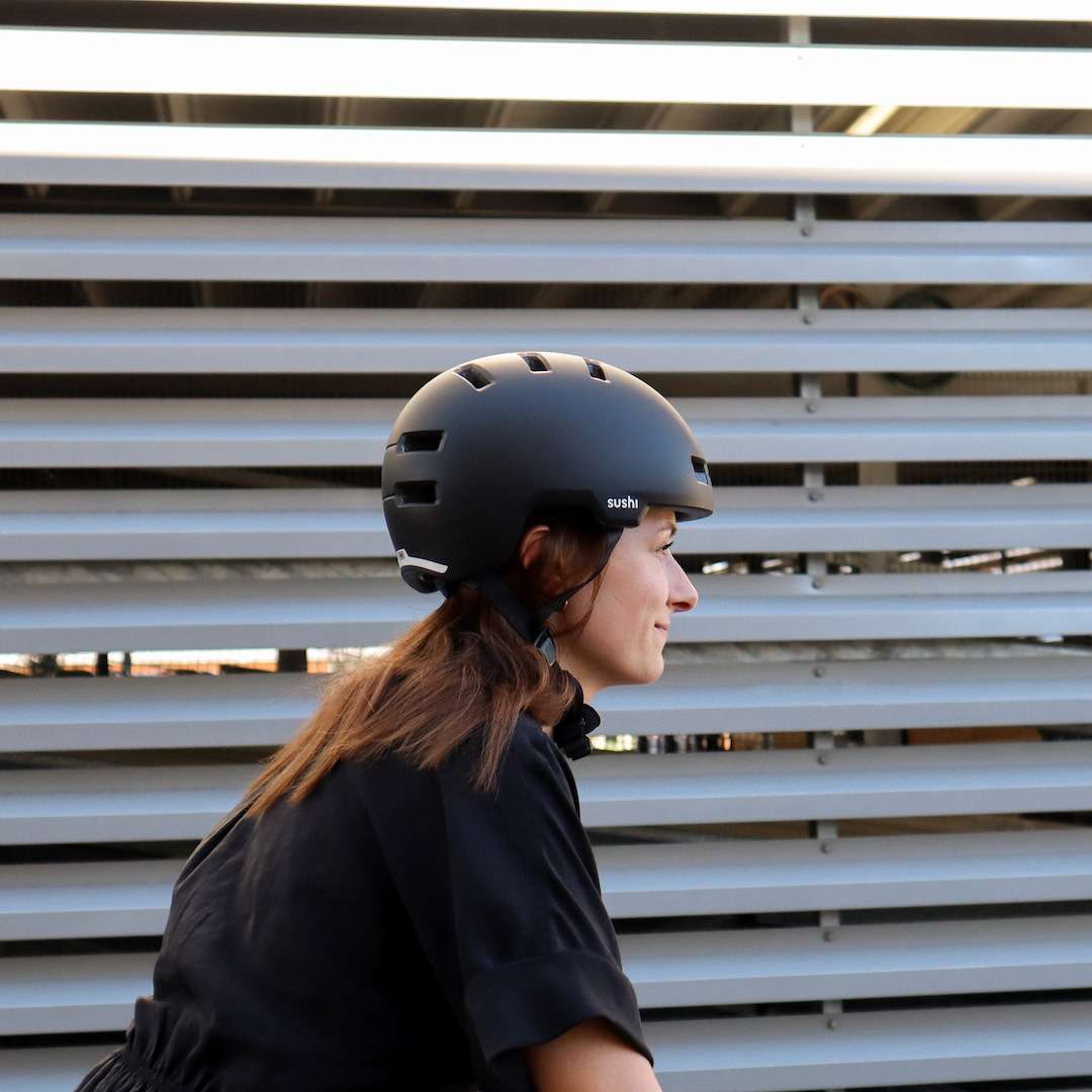 Frau mit ABUS Helm fährt Rad, Seitenprofil vom Helm mit SUSHI BIKES Logo 