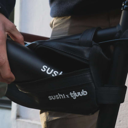 Person legt schwarzen SUSHI Akku in die geöffnete, am Rahmen befestigte tjuub Akkutasche