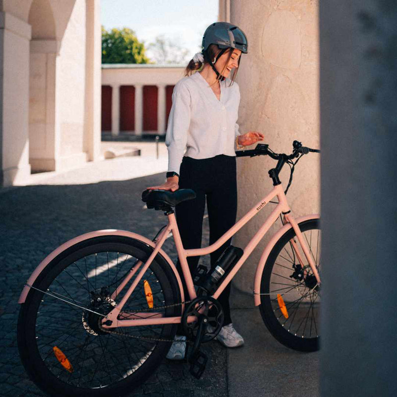 Frau mit Fahrradhelm hält Sushi Bike California Roll in rosa.